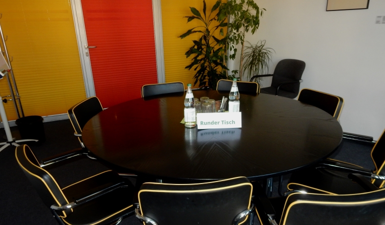 Runder Tisch in einem Zimmer mit Wasser und Gläsern und ein Schild "Runder Tisch".