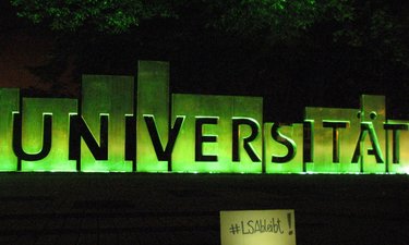 Schriftzug Universität in Magdeburg, nachts grün angestrahlt.