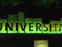 Schriftzug Universität in Magdeburg, nachts grün angestrahlt.