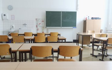 Leeres Klassenzimmer mit Stuhlreihen und Tafel.