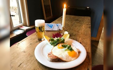 Gasthof mit Holztisch, einer Portion Strammer Max und einem frisch gezapftem Bier