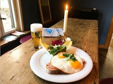 Gasthof mit Holztisch, einer Portion Strammer Max und einem frisch gezapftem Bier