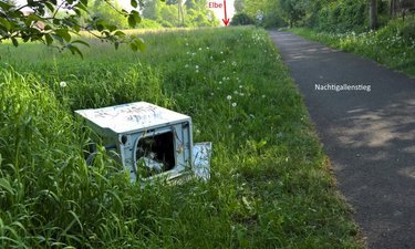 Alte Waschmaschine liegt auf der Wiese neben dem Nachtigallenstieg.