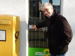 Olaf Meister zeigt am Fenster des Wahlkreisbüros auf das Logo des Freifunk-Aufklebers.