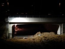 Neubau der westlichen Eisenbahnbrücke mit darunterliegender Tunneldecke im Dunkeln, von Bauscheinwerfern erleuchtet.