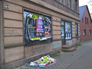 Durch herabgefallene Plakatpacken verdreckter Fußweg in Alt Fermersleben.