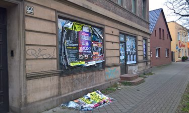 Durch herabgefallene Plakatpacken verdreckter Fußweg in Alt Fermersleben.