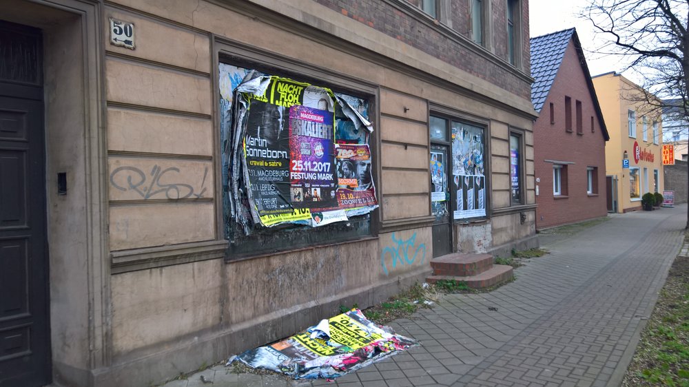 Durch herabgefallene Plakatpacken verdreckter Fußweg in Alt Fermersleben.