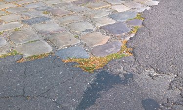 Reparaturbedürftige Straße mit Asphalt und Kopfsteinpflaster.